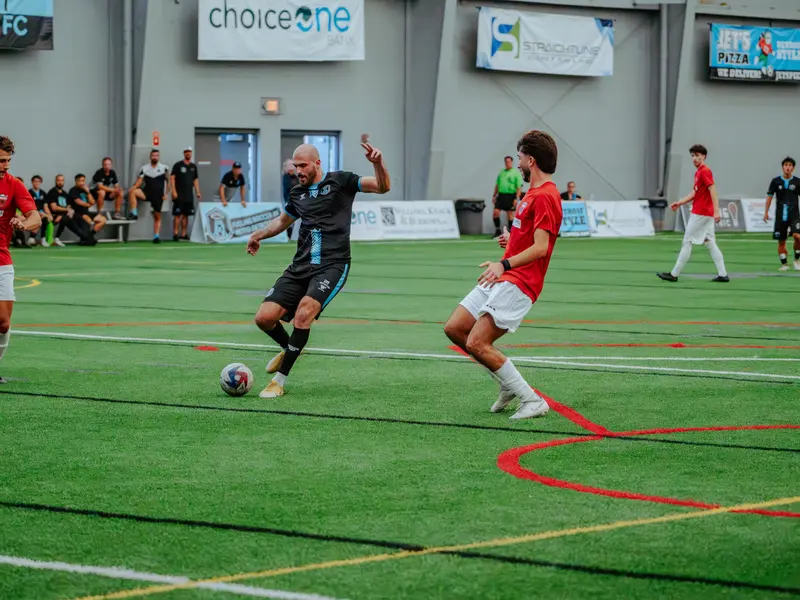 A Detroit Metro FC player strikes the ball between two defenders