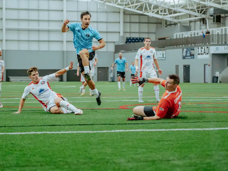 A Detroit Metro FC player rides a sliding tackle in front of goal