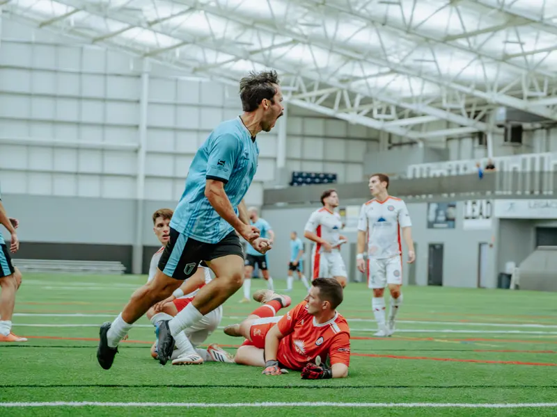 A Detroit Metro FC player carries the ball past a fallen defender