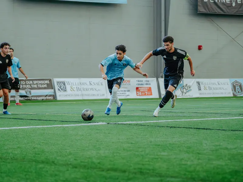 A Detroit Metro FC player drives between two opponents
